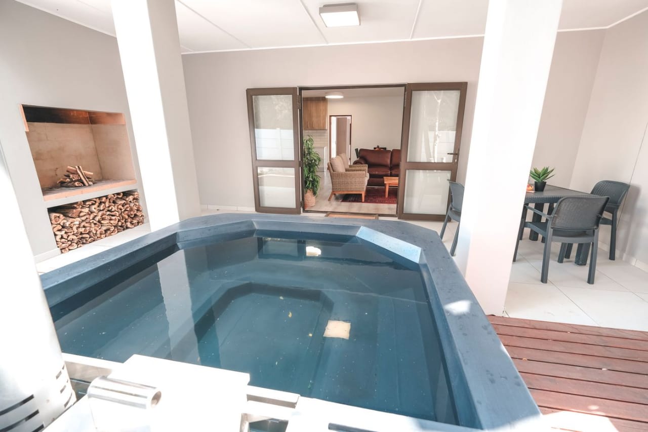 Covered patio with a built-in hot tub (Bamboo Apartment), wood-burning braai and open doors to the living room