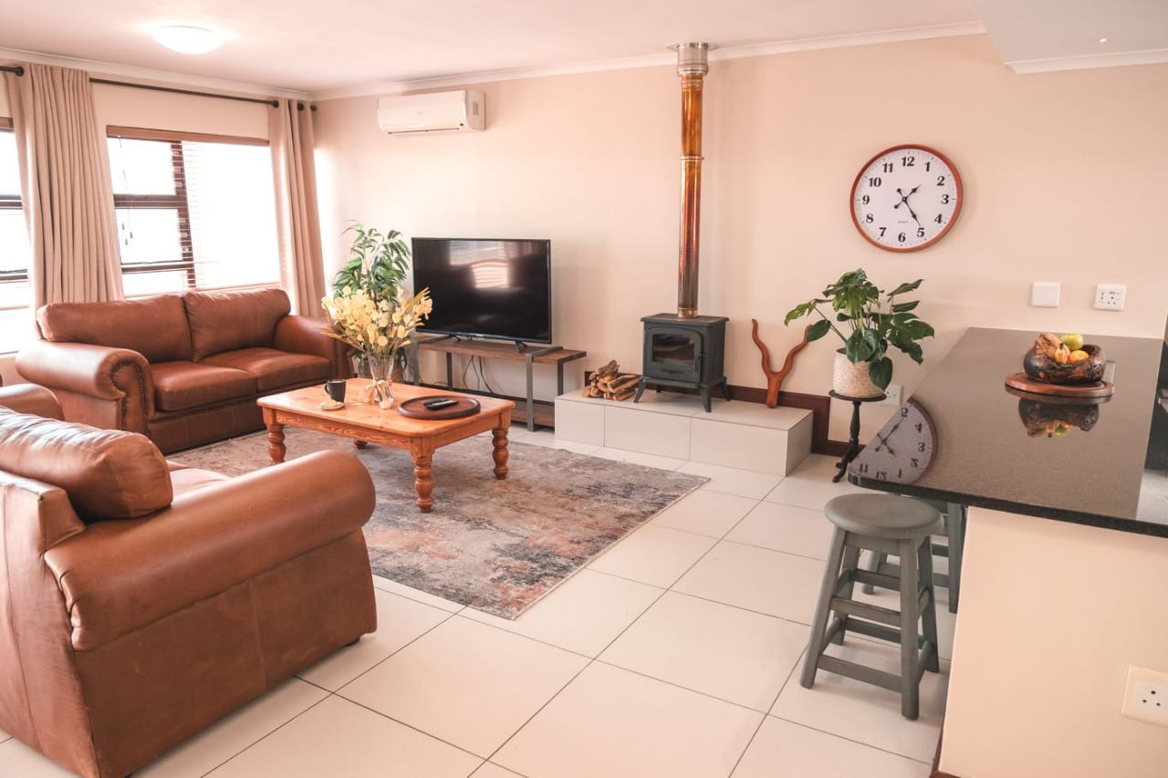 Open-plan living room in Whale Apartment with brown leather sofas, an indoor fireplace and kitchen breakfast bar